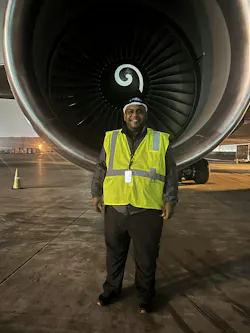A man wearing a high-visibility vest standing in front of an airplane engine A man wearing a high-visibility vest standing in front of an airplane engine
