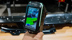 A handheld device with a screen showing a rendering of a piece of metal that's sitting on the ground a few feet away A handheld device with a screen showing a rendering of a piece of metal that's sitting on the ground a few feet away