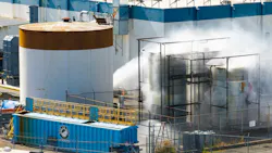 An aerial photograph of a large facility with water spraying onto one of the buildings An aerial photograph of a large facility with water spraying onto one of the buildings
