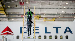 Two technicians climbing down a raised platform next to an airplane with text on the side that reads: DELTA