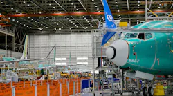 A wide shot of an aircraft production warehouse, with airplanes lined up among machinery