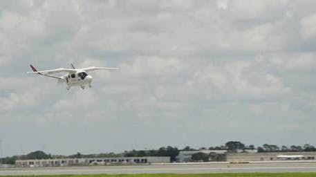 A white aircraft flying above an airport runway