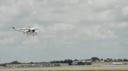 A white aircraft flying above an airport runway A white aircraft flying above an airport runway