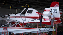 A red and white seaplane parked on a platform while a man checks a rear compartment A red and white seaplane parked on a platform while a man checks a rear compartment