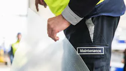 A technician wearing pants with a patch that says, 'MAINTENANCE' holding a piece of clear film with riblets on it A technician wearing pants with a patch that says, 'MAINTENANCE' holding a piece of clear film with riblets on it