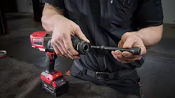 A person holding a large hammer chisel tool, holding the bit separate from the base, which is red and black A person holding a large hammer chisel tool, holding the bit separate from the base, which is red and black