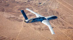 A gray airplane flying over desert landscape