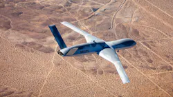 A gray airplane flying over desert landscape A gray airplane flying over desert landscape