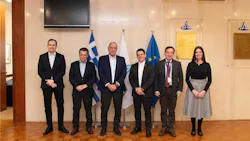 A group of professionals wearing business attire and standing in a line in front of three flags while smiling at the camera A group of professionals wearing business attire and standing in a line in front of three flags while smiling at the camera