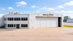 An outdoor shot of a warehouse-type facility with a sign that reads: West Star Aviation underneath a blue sky with clouds An outdoor shot of a warehouse-type facility with a sign that reads: West Star Aviation underneath a blue sky with clouds