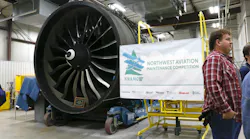 An airplane engine next to a banner that reads: NWAMC Northwest Aviation Maintenance Competition An airplane engine next to a banner that reads: NWAMC Northwest Aviation Maintenance Competition