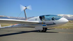 A small electric aircraft with a pilot in the cockpit landing on a runway A small electric aircraft with a pilot in the cockpit landing on a runway