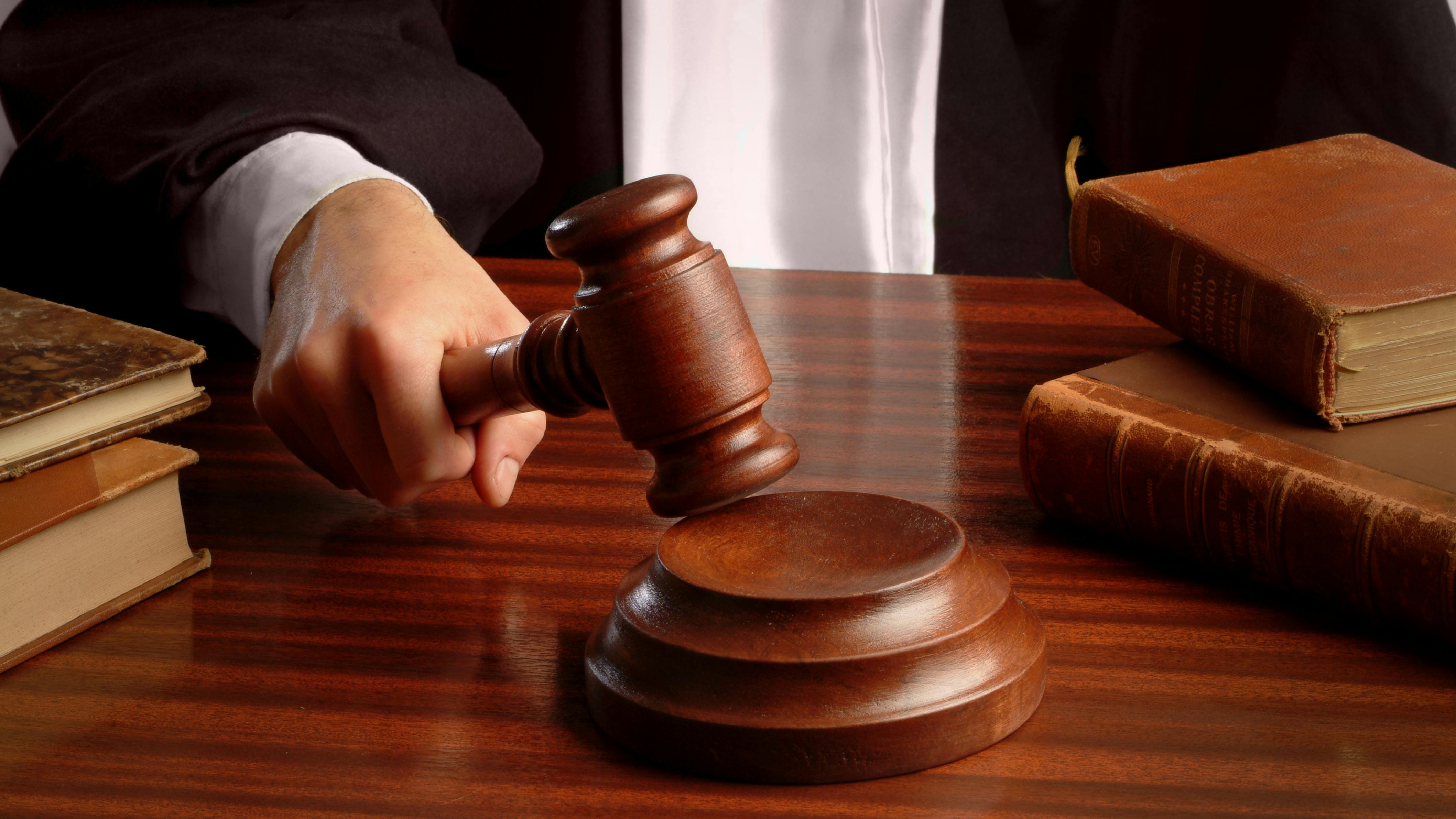 A close-up shot of a judge pounding a gavel on a desk, focusing in on the hand holding the gavel