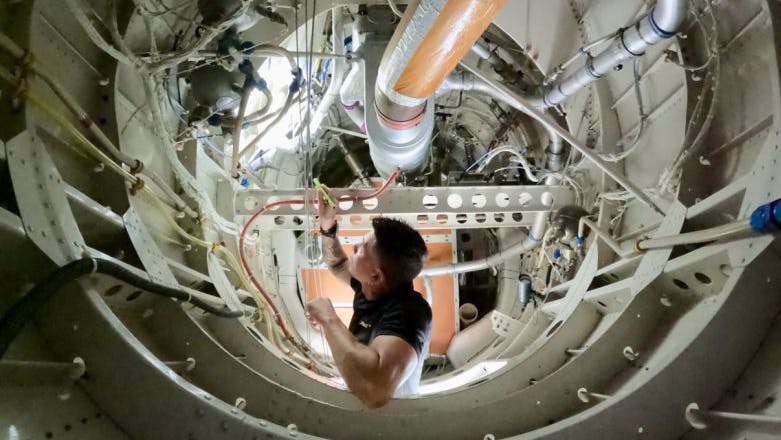 A technician working inside of an airplane engine