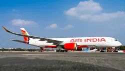 A white airplane with red accents and text on the side that reads: Air India A white airplane with red accents and text on the side that reads: Air India