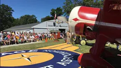 A close-up image of a red vintage airplane with a crowd in the background A close-up image of a red vintage airplane with a crowd in the background