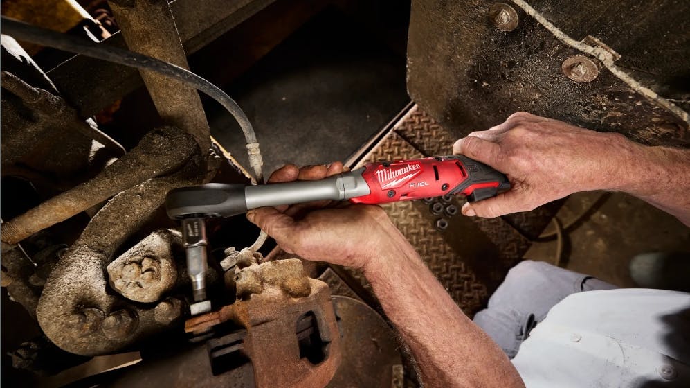 A technician using a tool to access a tight space inside a piece of machinery