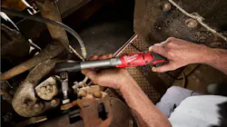 A technician using a tool to access a tight space inside a piece of machinery A technician using a tool to access a tight space inside a piece of machinery