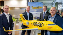 Four men wearing suits smiling at the camera while standing next to a yellow model airplane with text printed on the side that reads: ADAC Ambulance