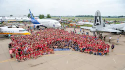 A huge crowd of people wearing red shirts and standing in front of a collection of airplanes A huge crowd of people wearing red shirts and standing in front of a collection of airplanes