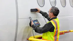 A man wearing a high-visibility vest holding a tool up to the side of an airplane while holding a screen A man wearing a high-visibility vest holding a tool up to the side of an airplane while holding a screen