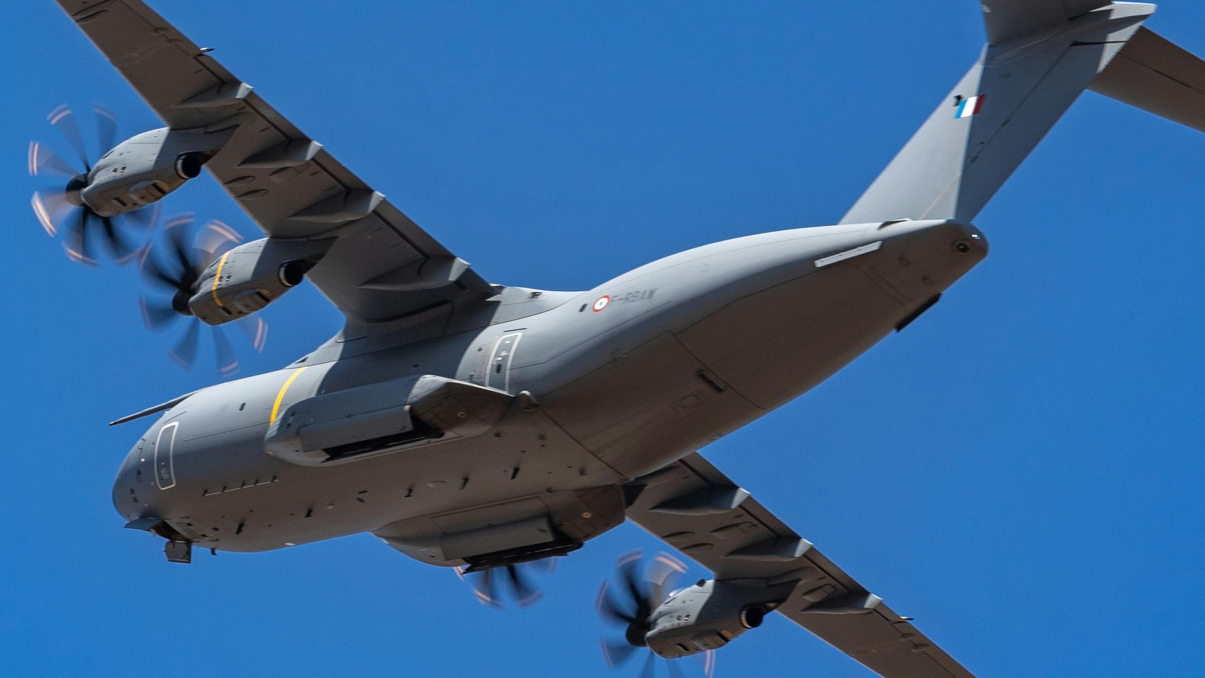 A gray military aircraft flying in front of a blue sky