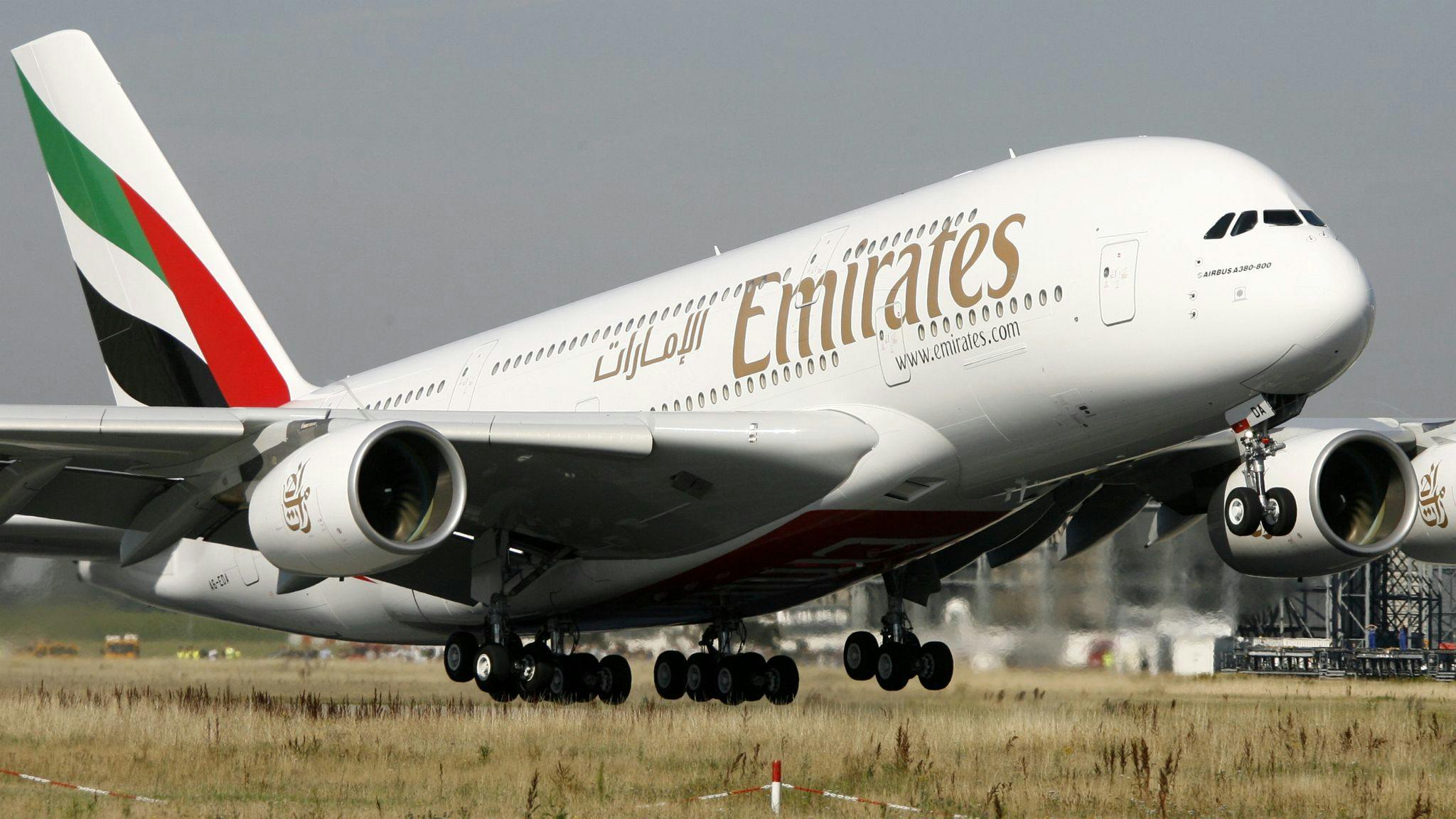A large white airplane with red and green accents on the tail and the word 'EMIRATES' printed on the side