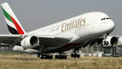 A large white airplane with red and green accents on the tail and the word 'EMIRATES' printed on the side A large white airplane with red and green accents on the tail and the word 'EMIRATES' printed on the side
