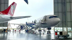 An airplane parked halfway inside a maintenance hangar, with a technician walking out the door An airplane parked halfway inside a maintenance hangar, with a technician walking out the door