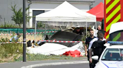 A white tent set up over the remnants of a plane crash, with a police officer standing in the foreground