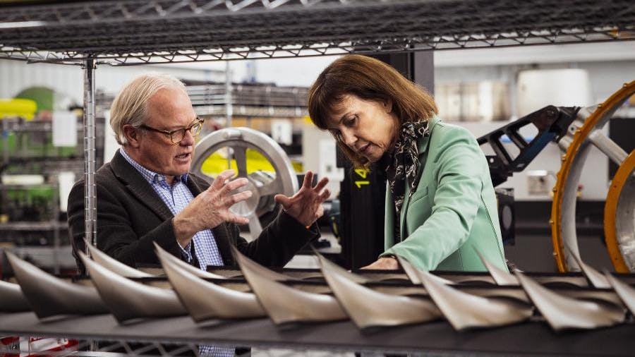 A man and woman talking to each other while looking at a row of engine parts
