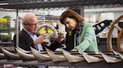 A man and woman talking to each other while looking at a row of engine parts