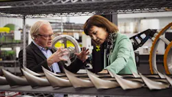 A man and woman talking to each other while looking at a row of engine parts