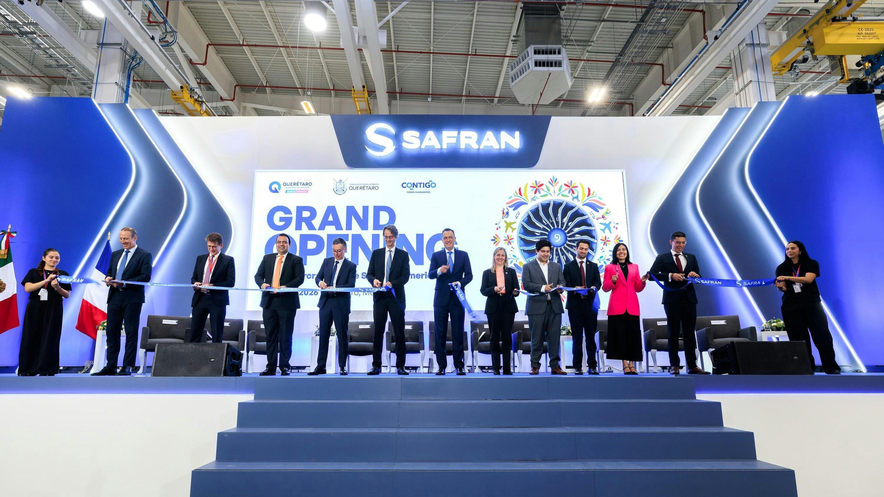 A line of people wearing business attire cutting a large ribbon in front of a backdrop that reads: SAFRAN Grand Opening