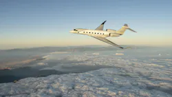 A cream-colored aircraft flying above a mountainous region and clouds