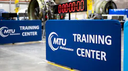 Two signs that read, 'MTU Maintenance Training Center' standing near a clock set at 00:00