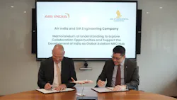 Two men wearing suits sitting at a table and signing pieces of paper, with text on a board behind them that reads: Air India and SIA Engineering Company Memorandum of Understanding to Explore Collaboration Opportunities and Support the Development of India as a Global Aviation MRO Hub