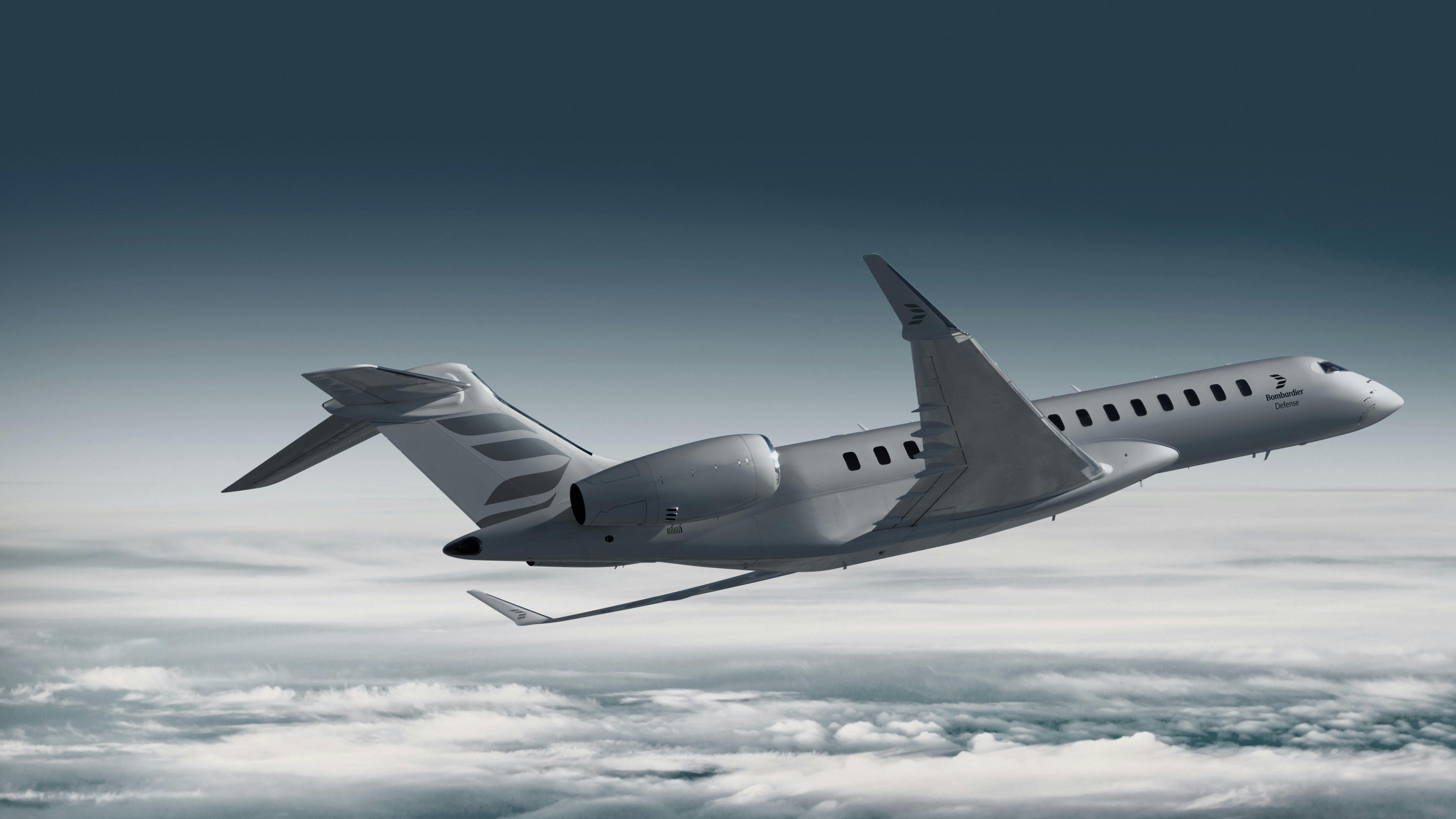 A gray airplane flying over a blanket of clouds in a dark sky