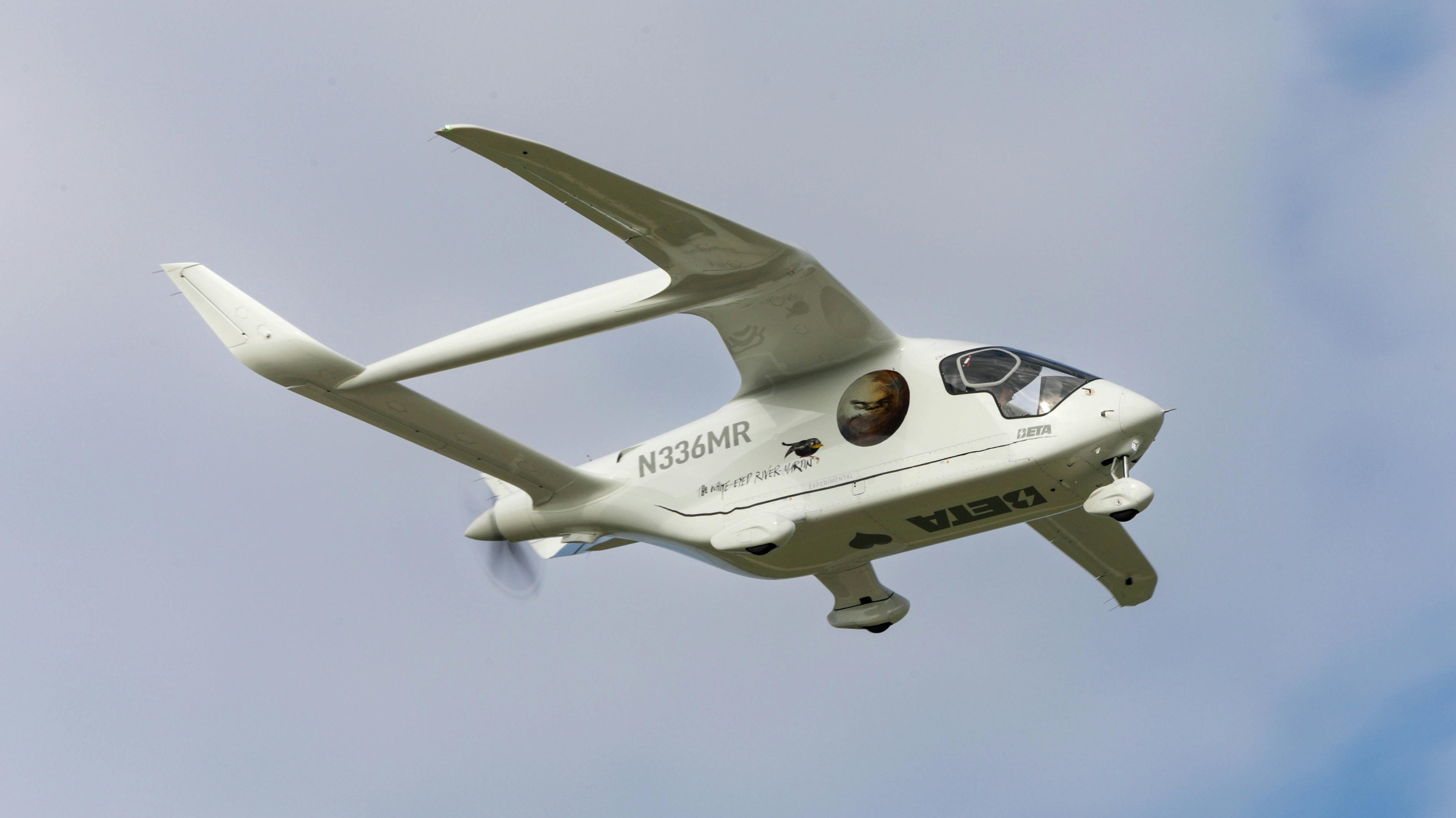 A small white electric aircraft flying in a clear blue sky