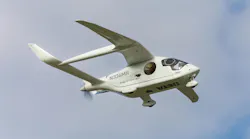 A small white electric aircraft flying in a clear blue sky