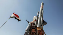 A photograph of a military soldier with a missile standing under a flag