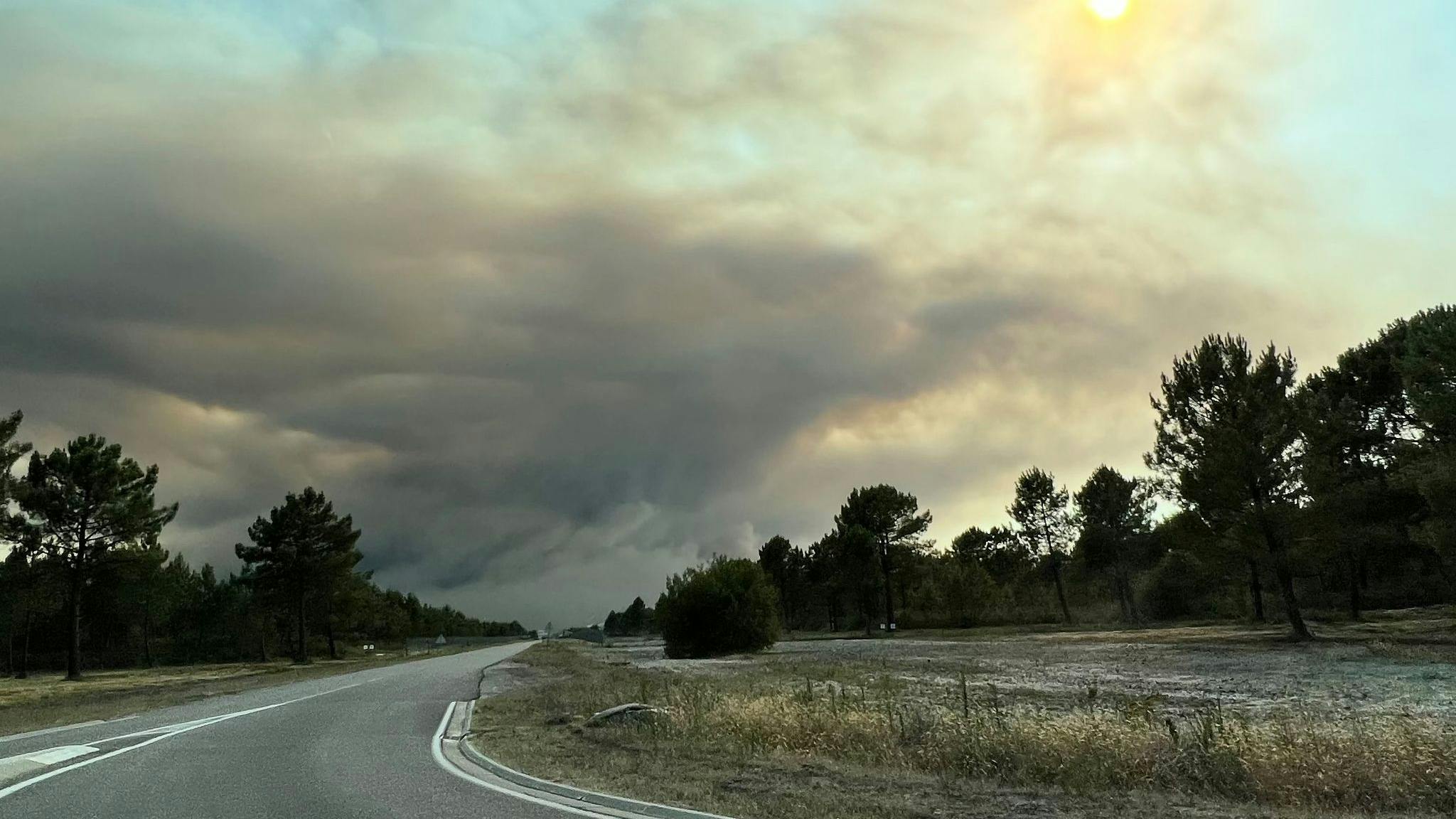 Dense clouds of smoke from a forest fire drift across a country road on the Atlantic coast about 60 southwest of Bordeaux.