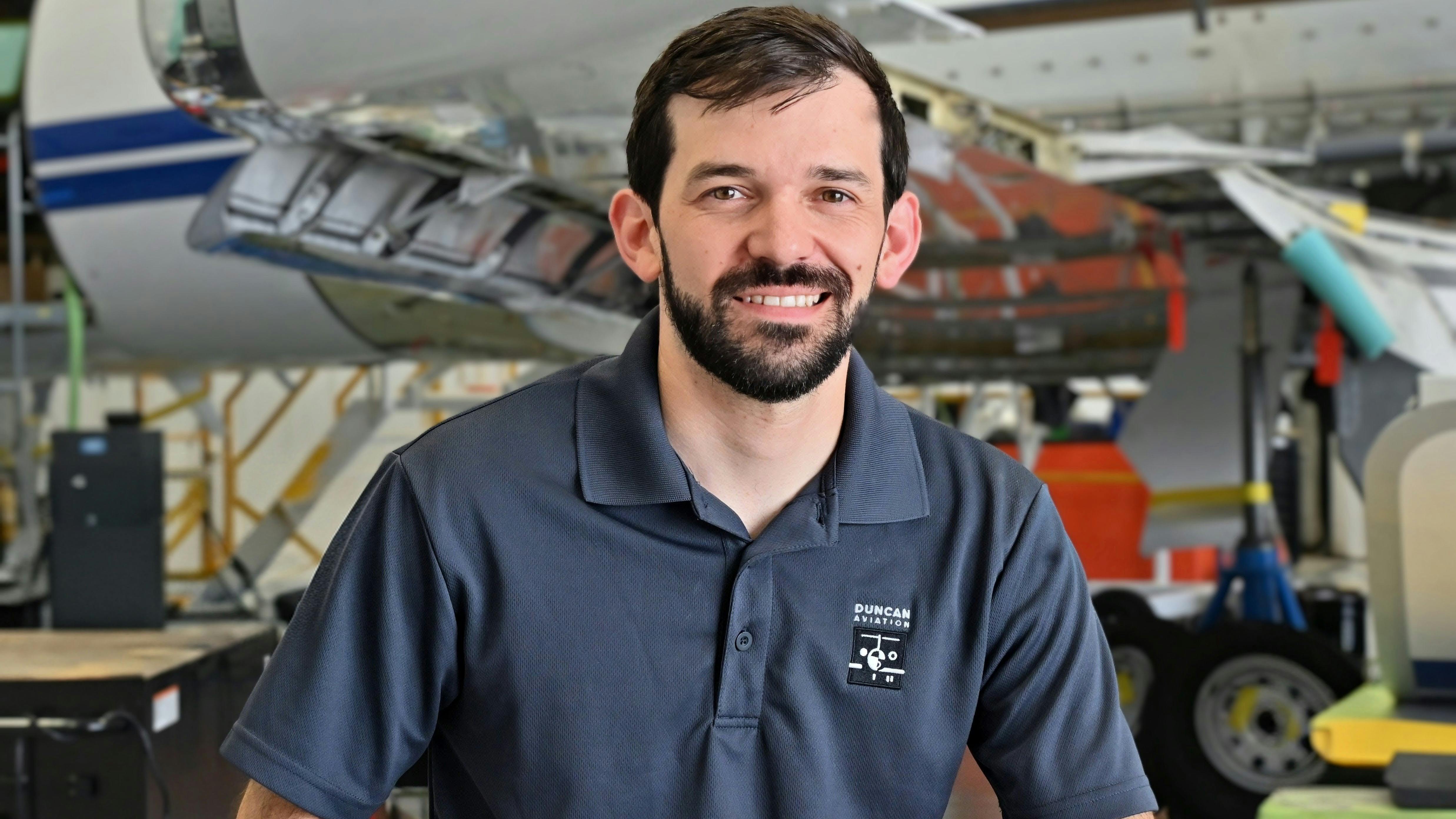 A man wearing a navy blue polo smiling at the camera