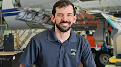 A man wearing a navy blue polo smiling at the camera