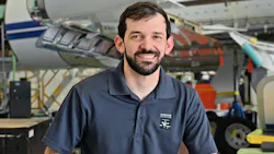 A man wearing a navy blue polo smiling at the camera