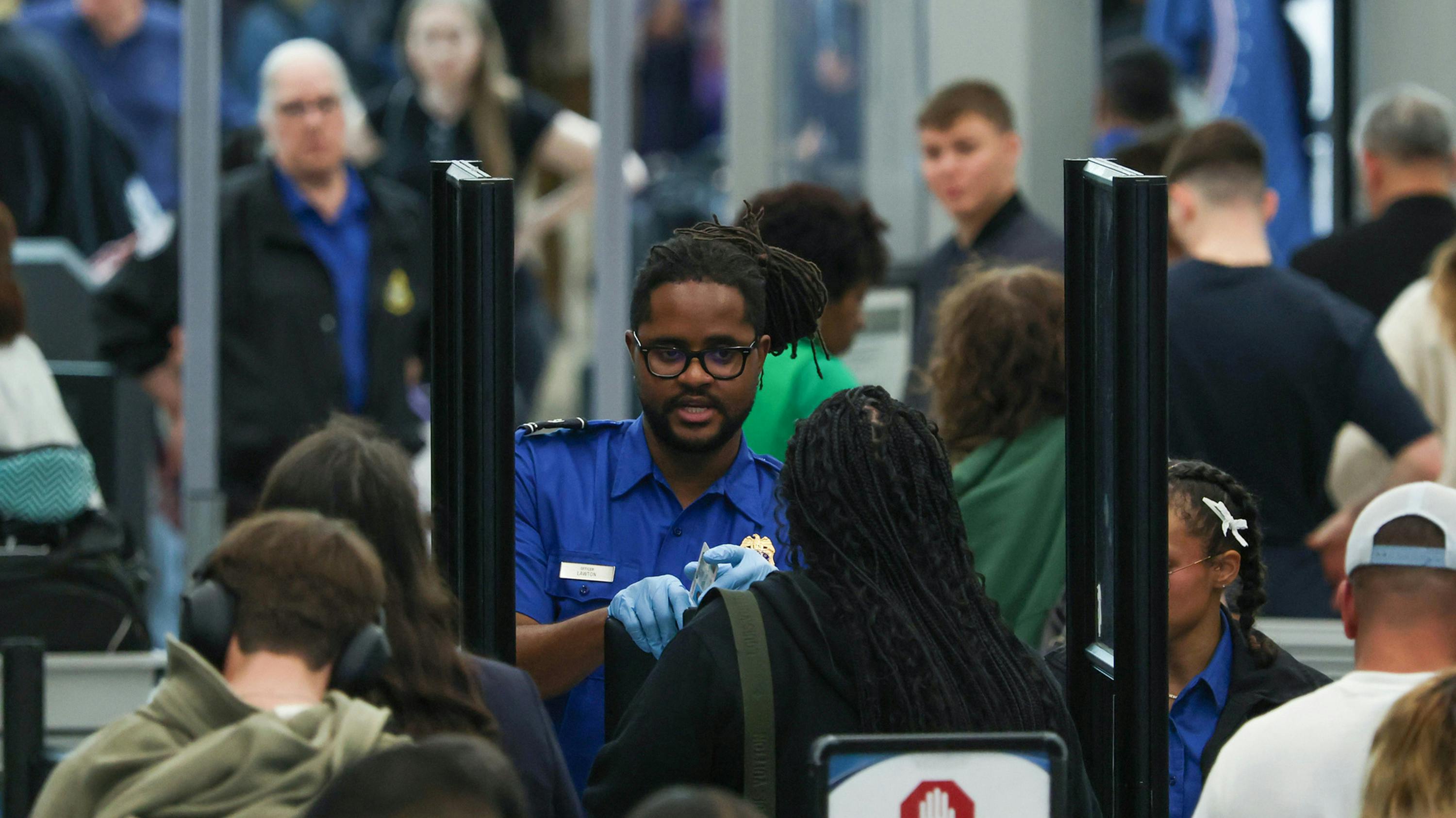 A TSA agent checks a passenger's identification in a security line at O'Hare International Airport, April 14, 2026, in Chicago.