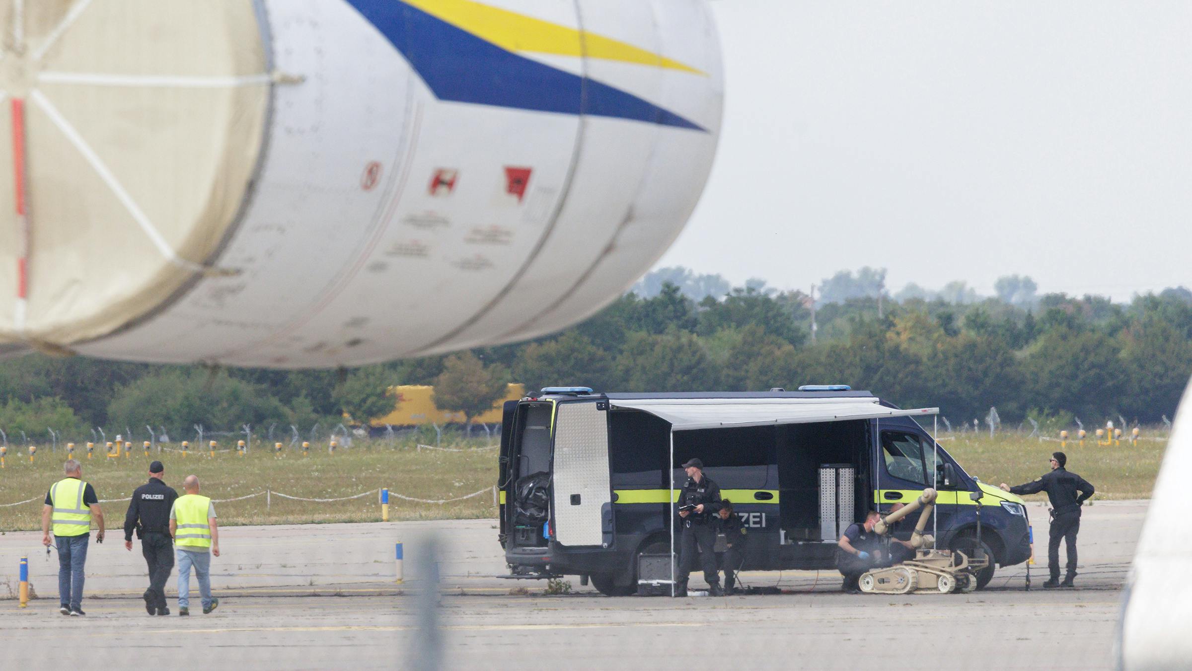 Police investigators work on the tarmac with a robot that is capable, amongst other things, of defusing explosives, near to Ukrainian Antonov cargo plane at Leipzig/Halle Airport on Aug. 5, 2026, near Leipzig, Germany. Airport workers reportedly discovered a drone yesterday on the tarmac near an Antonov at the airport that was equipped with an explosives detonator and an unidentified substance. Additionally, a DHL cargo plane that took off from the airport late last night collided with a small object, causing minor damage. (Jens Schlueter/Getty Images/TNS)
