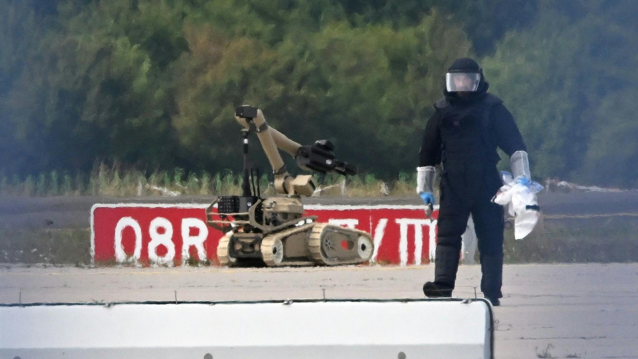 A forensic technician is working alongside a bomb-disposal robot near a Ukrainian aircraft at Leipzig/Halle Airport. Specialists from the Federal Police defused a drone equipped with an explosive device at the airport.