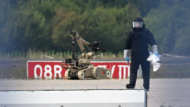 A forensic technician is working alongside a bomb-disposal robot near a Ukrainian aircraft at Leipzig/Halle Airport. Specialists from the Federal Police defused a drone equipped with an explosive device at the airport.