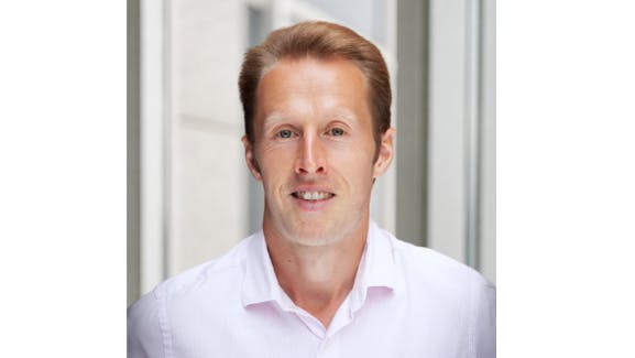 A man wearing a white collared shirt smiling at the camera